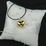 Bola Heart dans sa version or présenté sur un coussin pour alliances blanc parsemé de strass blancs.