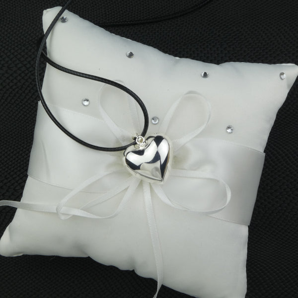 Bola Heart dans sa version argent présenté sur un coussin pour alliances blanc parsemé de strass blancs.
